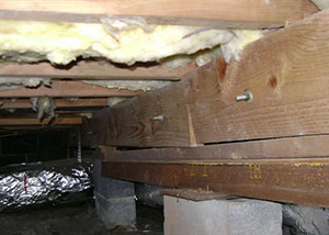 A sagging crawl space with concrete supports and wooden shimming a Lillington crawl space